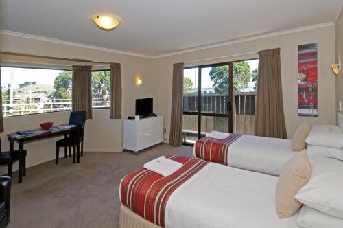 a hotel room with two beds and a desk at Airport Harbour Motel in Auckland