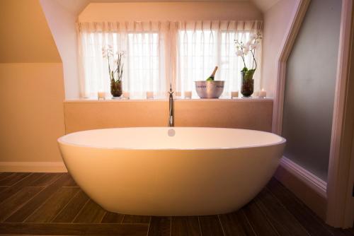 a bath tub in a bathroom with two windows at Danesfield House Hotel And Spa in Marlow