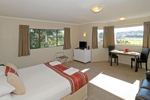 a hotel room with a bed and a desk and a table at Airport Harbour Motel in Auckland