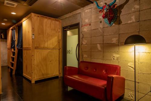 a red couch in a room with a brick wall at Midnight Rockers in Kanazawa