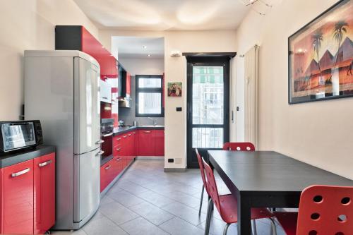 una cucina con armadi rossi, tavolo e frigorifero di Vanchiglietta Colourful Apartment a Torino