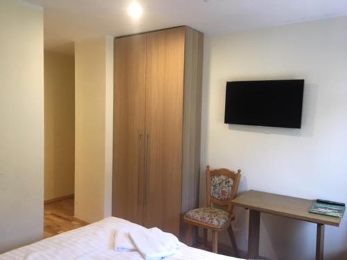 a bedroom with a desk and a cabinet with a television at Pension Eder - Joker card included in summer in Saalbach Hinterglemm