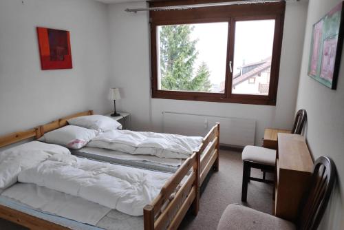FlumserbergにあるHaus Gran Solのベッド2台、テーブル、窓が備わる客室です。