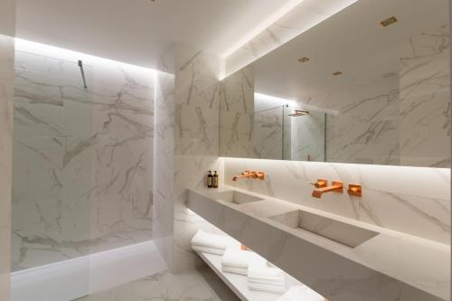 y baño con paredes de mármol blanco y ducha. en Azor Central Lodge en Ponta Delgada