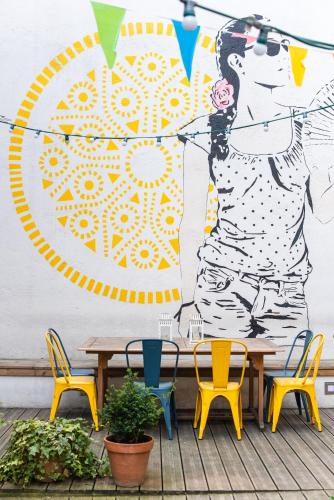a table and chairs in front of a mural at SLO Hostel Lyon Saxe in Lyon