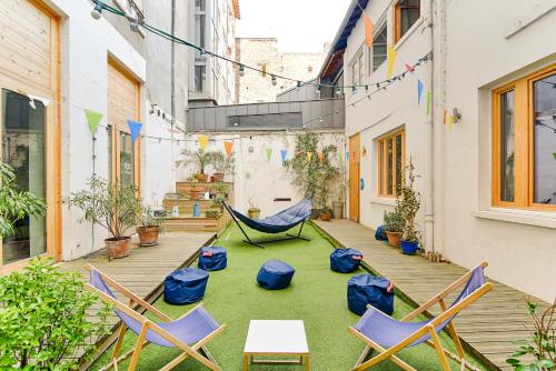 a patio area with tables, chairs and umbrellas at SLO Living Hostel in Lyon