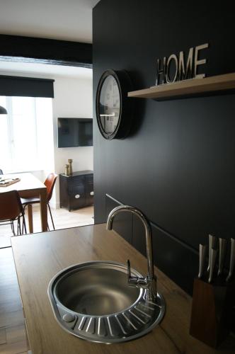 - un évier de cuisine avec une horloge murale dans l'établissement Le 1777, à Dinan