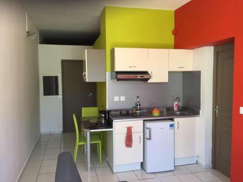 a kitchen with white appliances and green and red walls at COSY TAMARINS 1 à quelques pas du lagon in Sainte-Anne