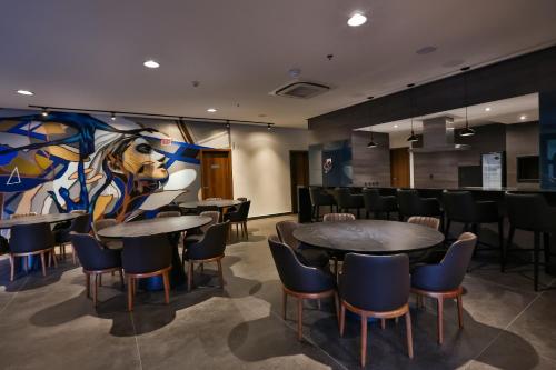 a conference room with tables and chairs and a painting at Quality Hotel Blumenau in Blumenau
