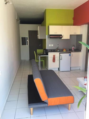 a kitchen with a couch in the middle of a room at COSY Tamarins 2 plage à quelques mètres à pied in Sainte-Anne