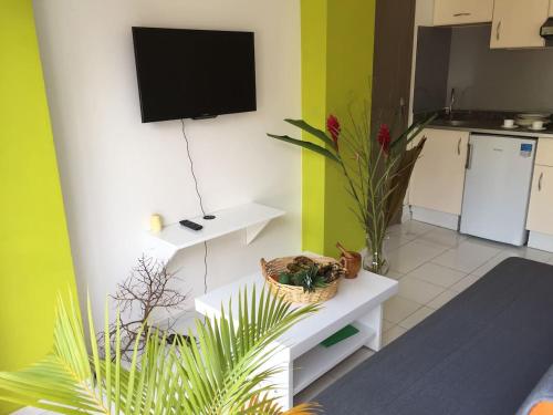 a living room with a flat screen tv on a wall at COSY Tamarins 2 plage à quelques mètres à pied in Sainte-Anne