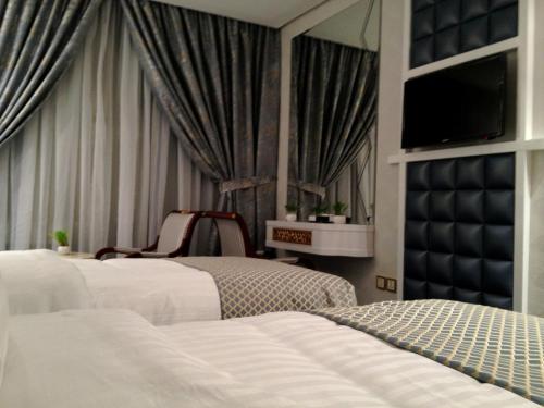 a bedroom with two beds and a chair and a television at Montana Al Azizia Hotel in Makkah