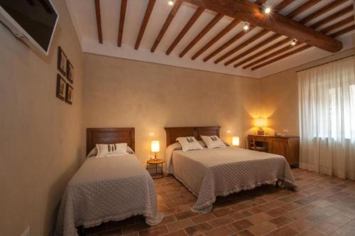 a bedroom with two beds and two lamps and a window at Le Camere Del Borgo in Montescudaio