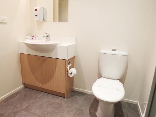 een badkamer met een wit toilet en een wastafel bij Nesuto Newhaven in Auckland