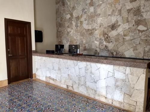 a bar in a hotel room with a stone wall at Hotel Catedral Valladolid Yucatan in Valladolid