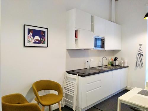 uma cozinha com armários brancos e duas cadeiras e uma mesa em Casa Italiano - BestBnB Garbatella em Roma