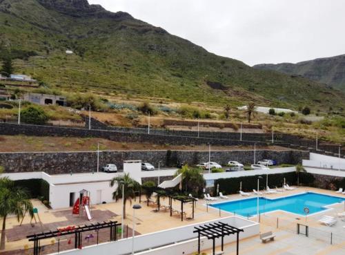 a building with a swimming pool next to a mountain at Faro Armonía in Bajamar
