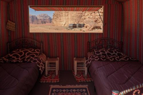 a room with two beds and a picture on the wall at Arabian Nights in Wadi Rum