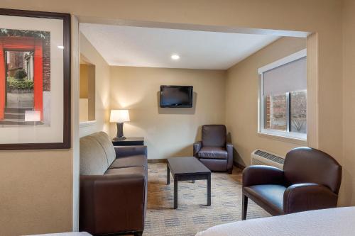 a waiting room with a couch and chairs and a tv at Studio 6 Suites Charlotte, NC - Tyvola Rd Executive Park in Charlotte