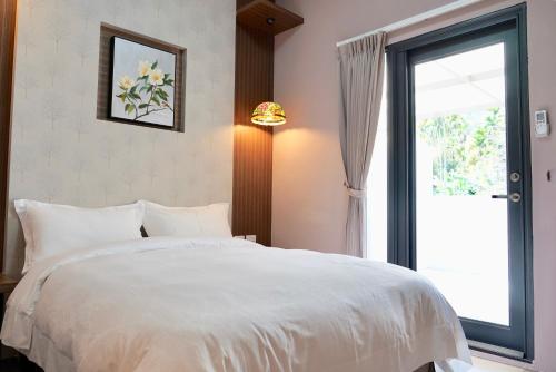 a bedroom with a white bed and a window at MTNY Hotel in Zhushan