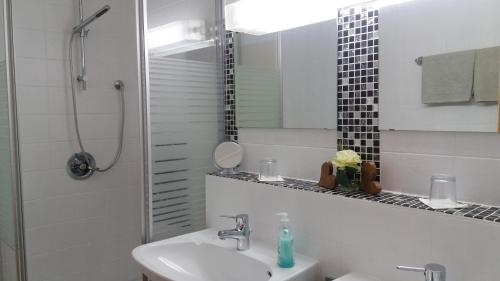 a white bathroom with a sink and a shower at Landhaus Schwaben in Schönmünzach