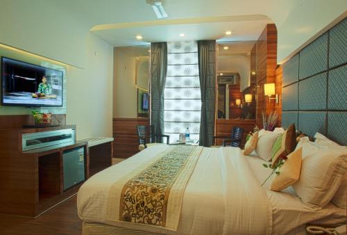 a bedroom with a large bed and a television at Hotel Delhi 55 -City Center in New Delhi