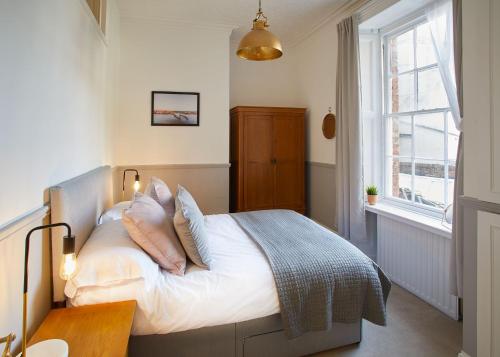 um quarto com uma cama com lençóis brancos e almofadas em Host & Stay - Havelock Place Apartment em Whitby