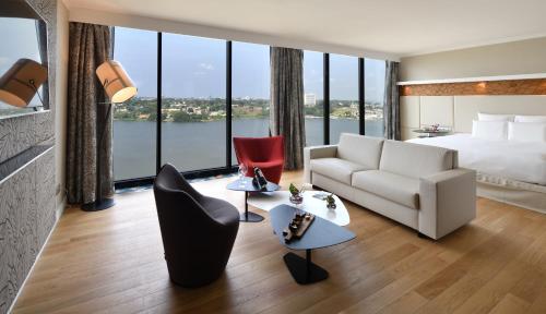 a hotel room with a bed and a large window at Pullman Abidjan in Abidjan
