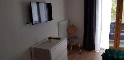 a room with a tv and a dresser and a chair at Pension Lischenhof in Ehrwald