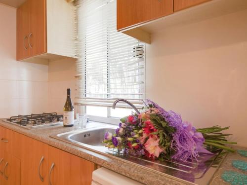 a kitchen sink with a bouquet of flowers and a bottle of wine at Nice chalet in a pine forest near the Adriatic sea in Cesenatico