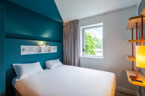a bedroom with a white bed and a window at ibis budget Gonesse in Gonesse