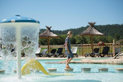 Młody chłopiec bawi się w fontannie w basenie. w obiekcie Camping l'Hirondelle Drôme w mieście Menglon