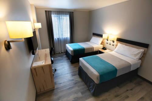 a hotel room with two beds and a window at Hotel Diego de Almagro Viña del Mar in Viña del Mar