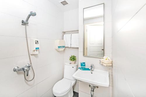 a white bathroom with a toilet and a sink at Hotel 81 Elegance in Singapore