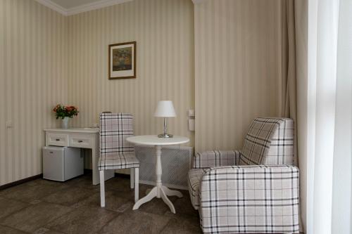 モスクワにあるDetol Hotelのデスク、椅子2脚、テーブルが備わる客室です。