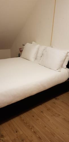 een bed met witte lakens en kussens in een kamer bij Vakantiehuis Katwijk in Katwijk