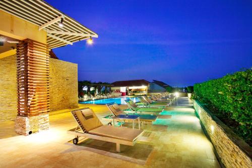 a patio with lounge chairs and a pool at night at Intimate Hotel Pattaya - SHA Extra Plus in Pattaya