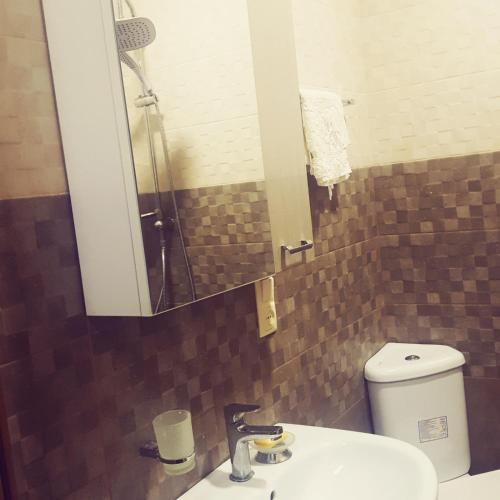 a bathroom with a sink and a mirror and a toilet at Here comes the sun in Batumi