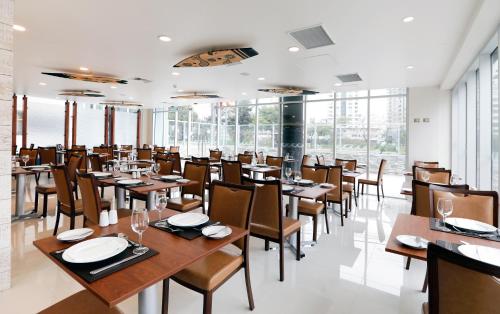 a restaurant with wooden tables and chairs and windows at Hotel Diego de Almagro Viña del Mar in Viña del Mar