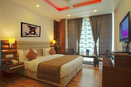 a bedroom with a large bed and a television at Hotel Delhi 55 -City Center in New Delhi