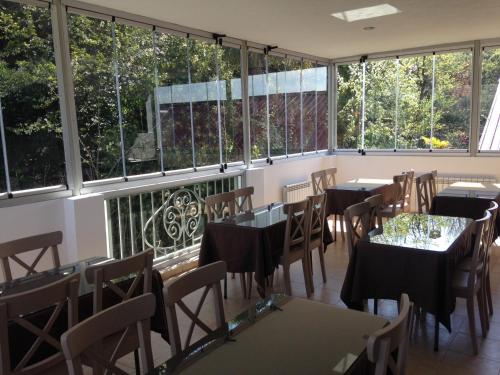 un restaurante con mesas, sillas y ventanas grandes en Center Villa Kutaisi en Kutaisi