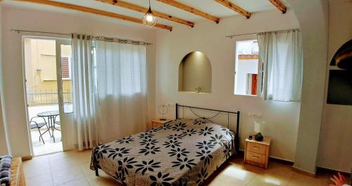 a bedroom with a bed and a table and windows at BEAUTIFUL HOUSE OF PSINTHOS in Psinthos