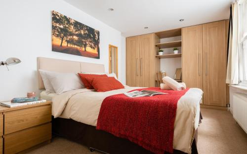 a bedroom with a bed with a red blanket at Classic Two-Bedroom Apartment Pimlico in London