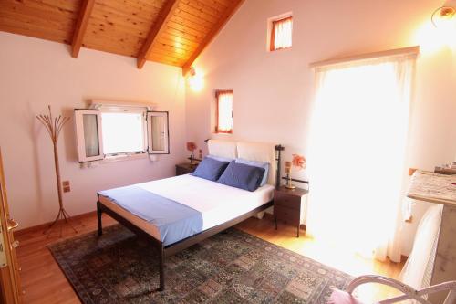 una camera da letto con un letto con lenzuola bianche e cuscini blu di Villa Fotismata - Chalet in the heart of Kalavryta a Kalavrita