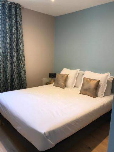 1 cama grande con sábanas y almohadas blancas en Villa st Louis, en Cabourg