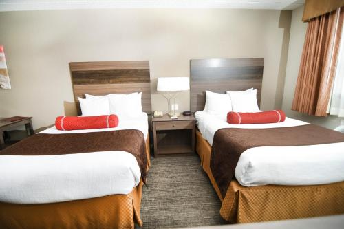 a hotel room with two beds with red pillows at Best Western Plus Sandusky Hotel & Suites in Sandusky