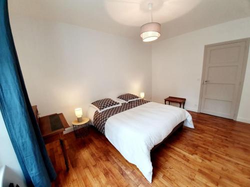 Un dormitorio con una gran cama blanca y suelos de madera. en Le Pilo, en Saint-Malo