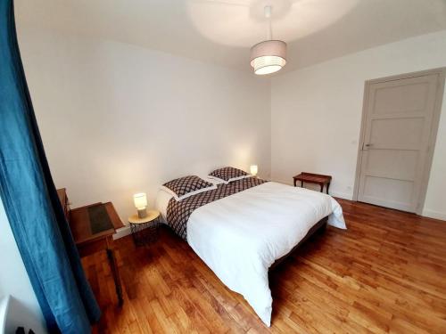 una camera da letto con un grande letto bianco e pavimenti in legno di Le Pilo a Saint Malo