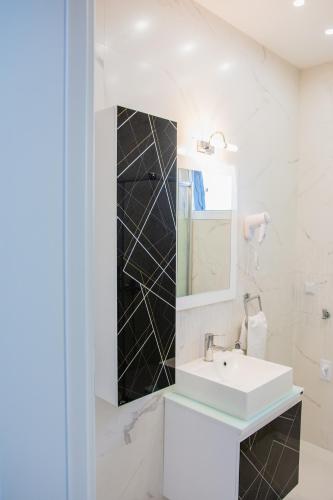 a white bathroom with a sink and a mirror at Grande Plus Apartment Dzungla in Doboj