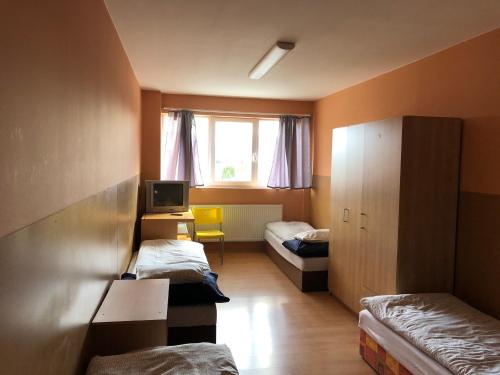 ストゥパヴァにあるApartments Stupavaのベッド2台、デスク、テレビが備わる客室です。
